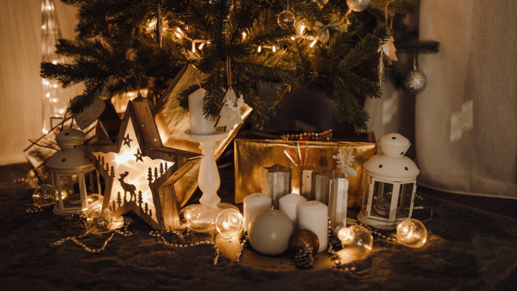 Figurki i ozdobne świece ustawione przy choince jako uzupełnienie świątecznej aranżacji